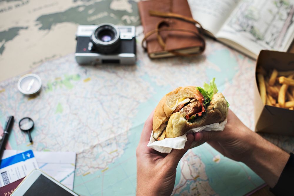 Closeup of hands holding hamburger over map background