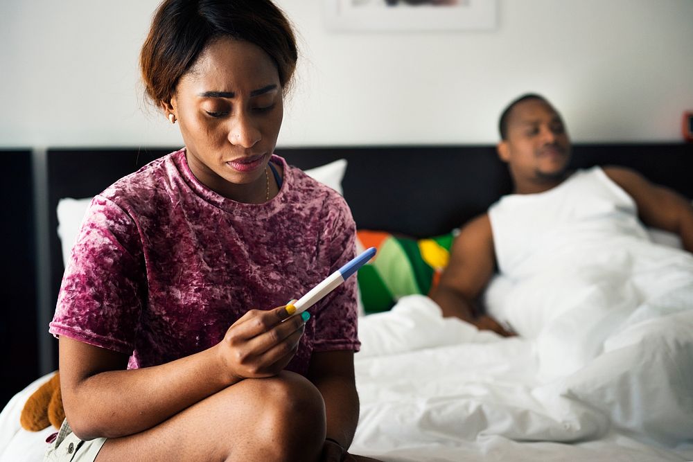 Black woman looking at pregnancy test
