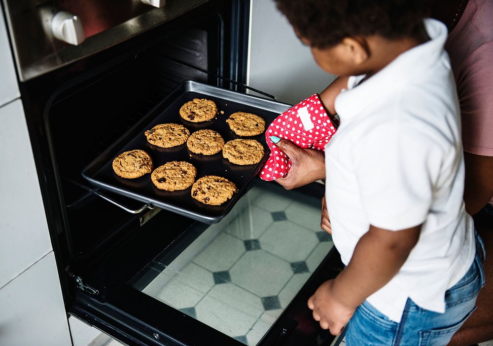 Black kid helping mom baking cookies