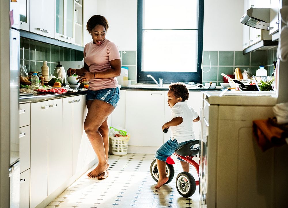 Black kid riding bicycle in the kitchen