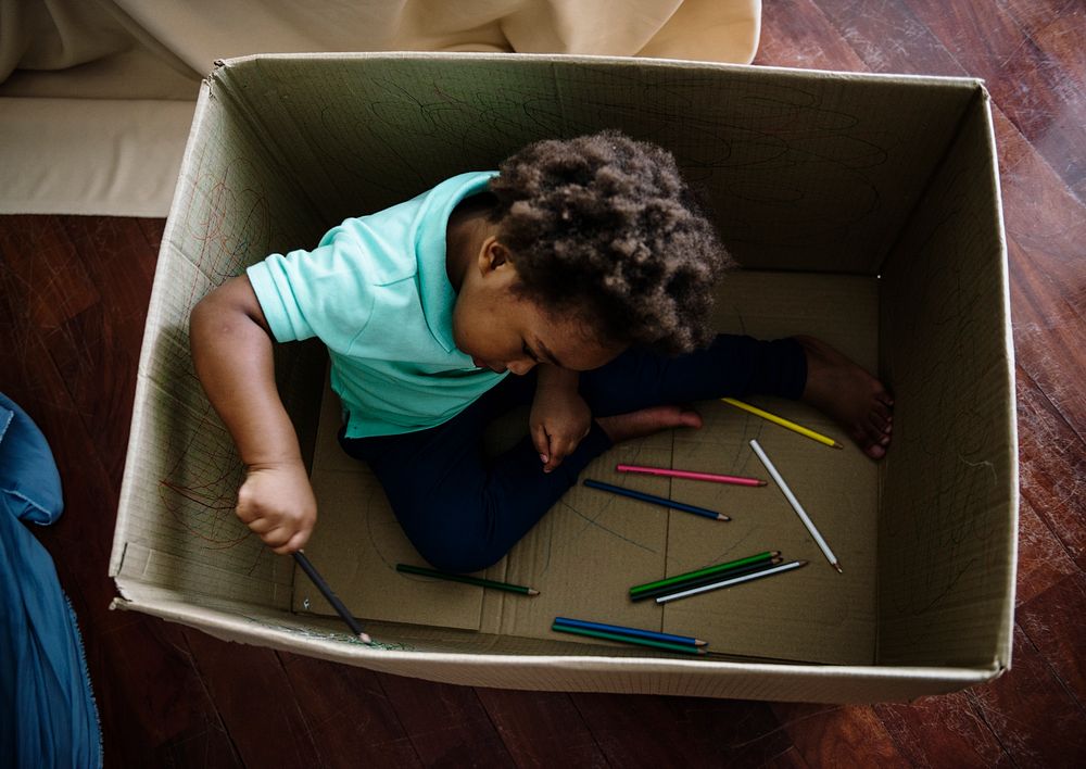 Black kid painting in a box