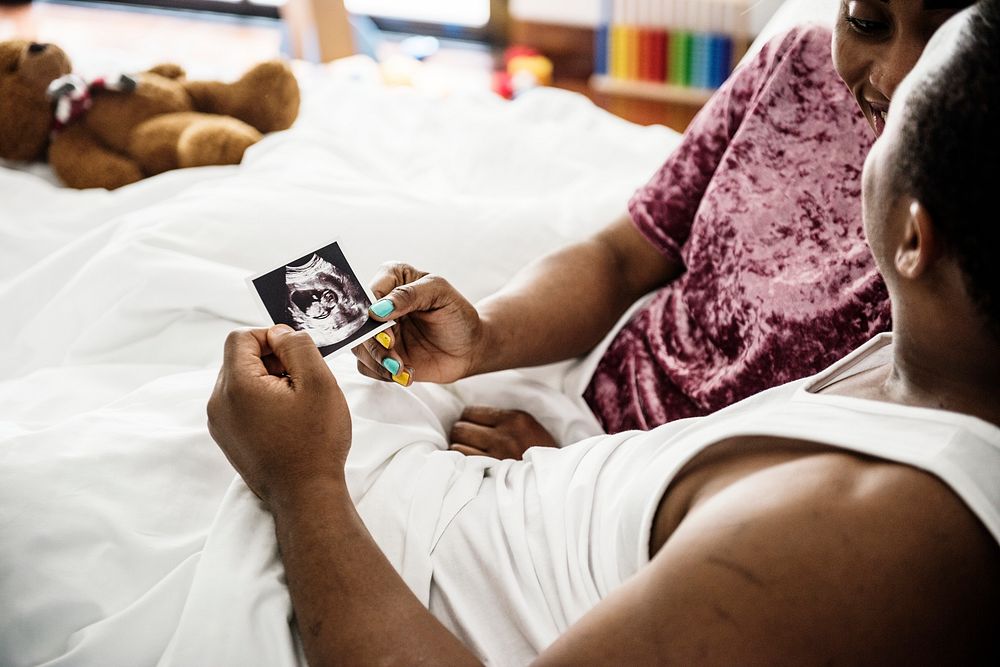 Black couple looking at baby ultrasound scan photo