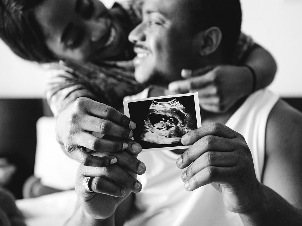 Black couple showing baby ultrasound scan photo