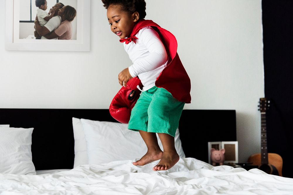 African descent kid jumping on the bed