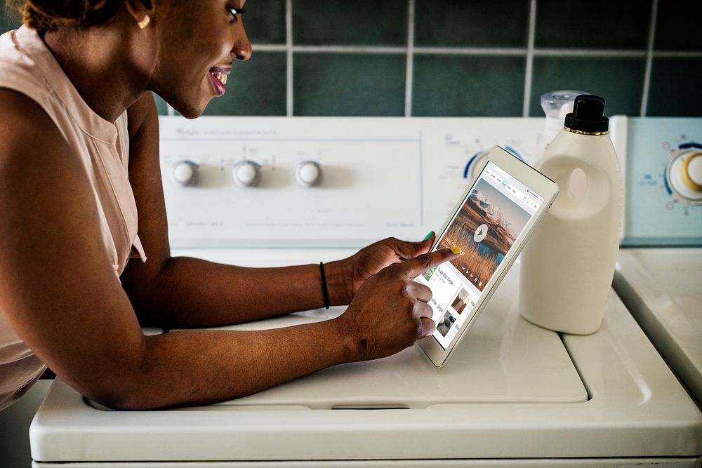 Black woman using digital tablet near the washing machine