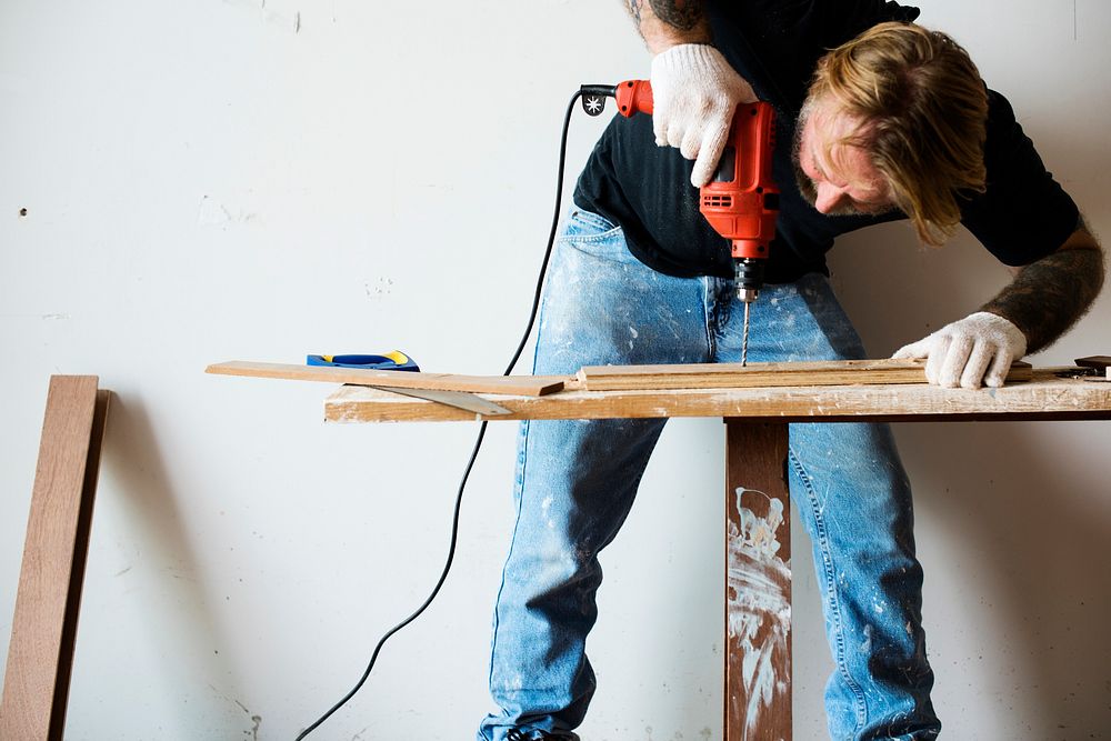 A carpenter using a drill on a wood