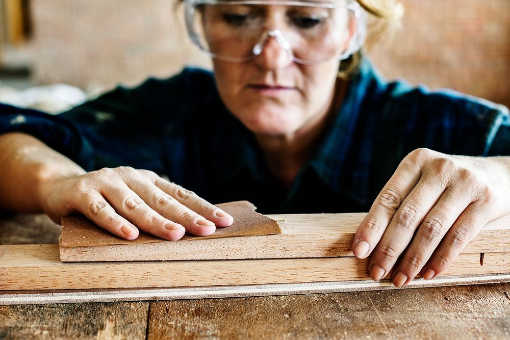 Woman carpenter using sandpaper on a wood