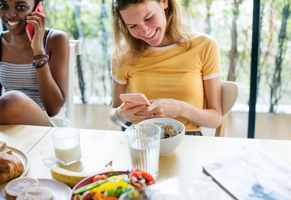 Women using mobile phones during breakfast
