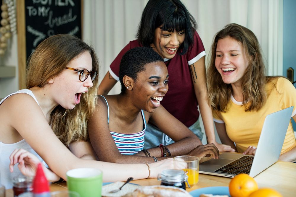 Group of diverse friends looking at computer laptop with surprise face expression