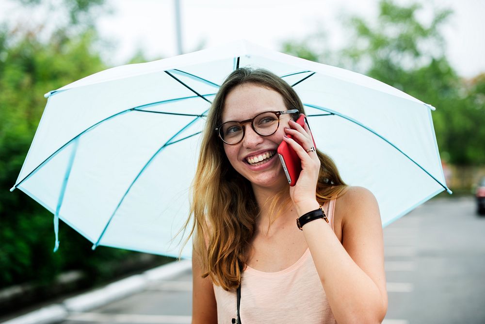 A woman using a mobile phone under an umbrella