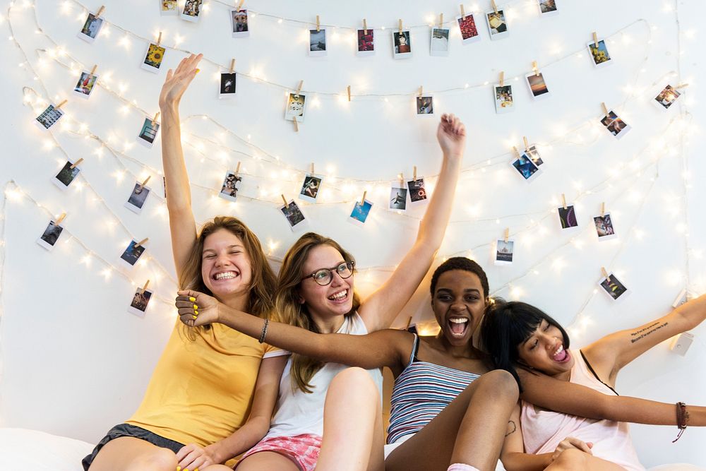 Group of diverse women sitting on bed together
