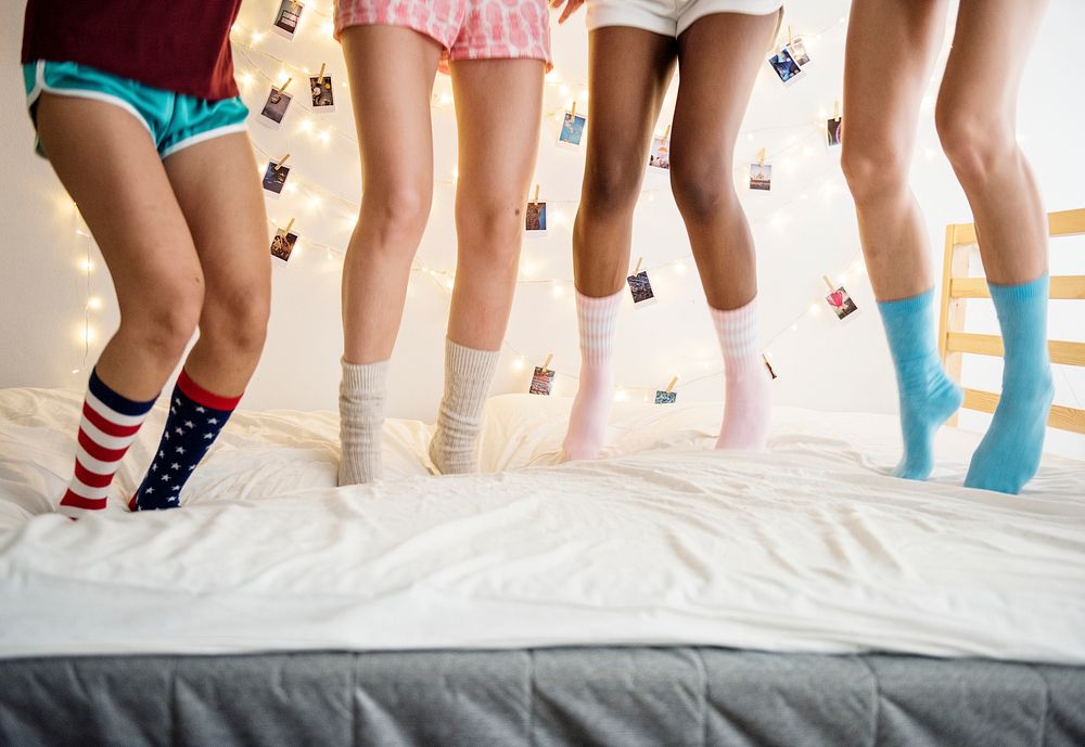 Closeup of four pairs of legs with socks jumping on the bed
