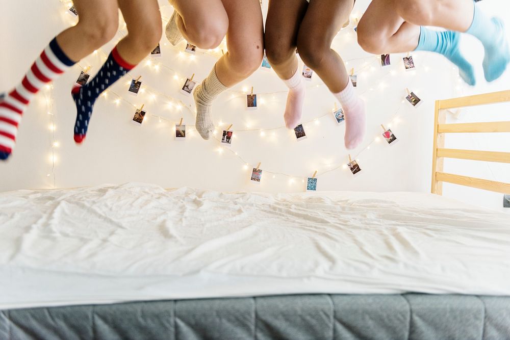 Closeup of two pairs of legs with socks jumping on the bed