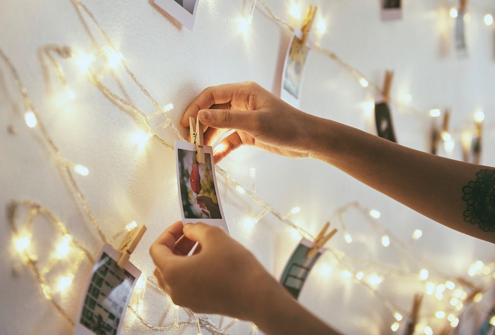 Closeup of hands with photos hanging on decoration lights 