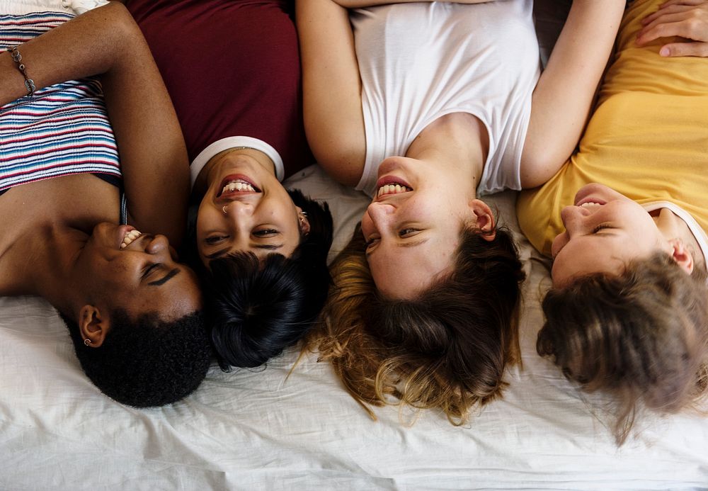 Group of diverse women lying on bed together