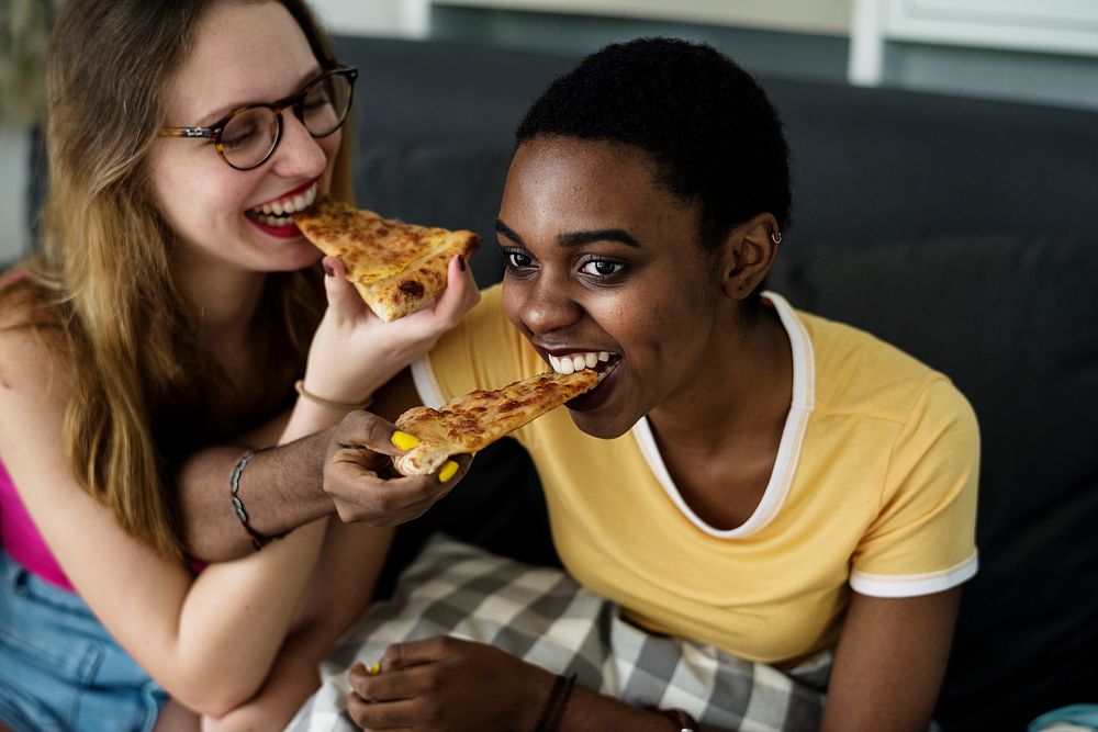 Diverse women eating pizza together
