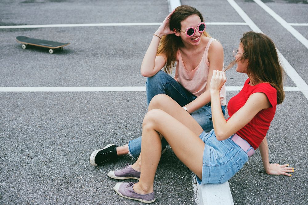 Woman friends sitting on the ground and talking together 