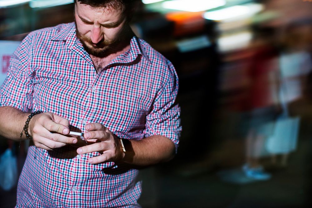 Closeup of a man using mobile phone in the dark with long exposure light