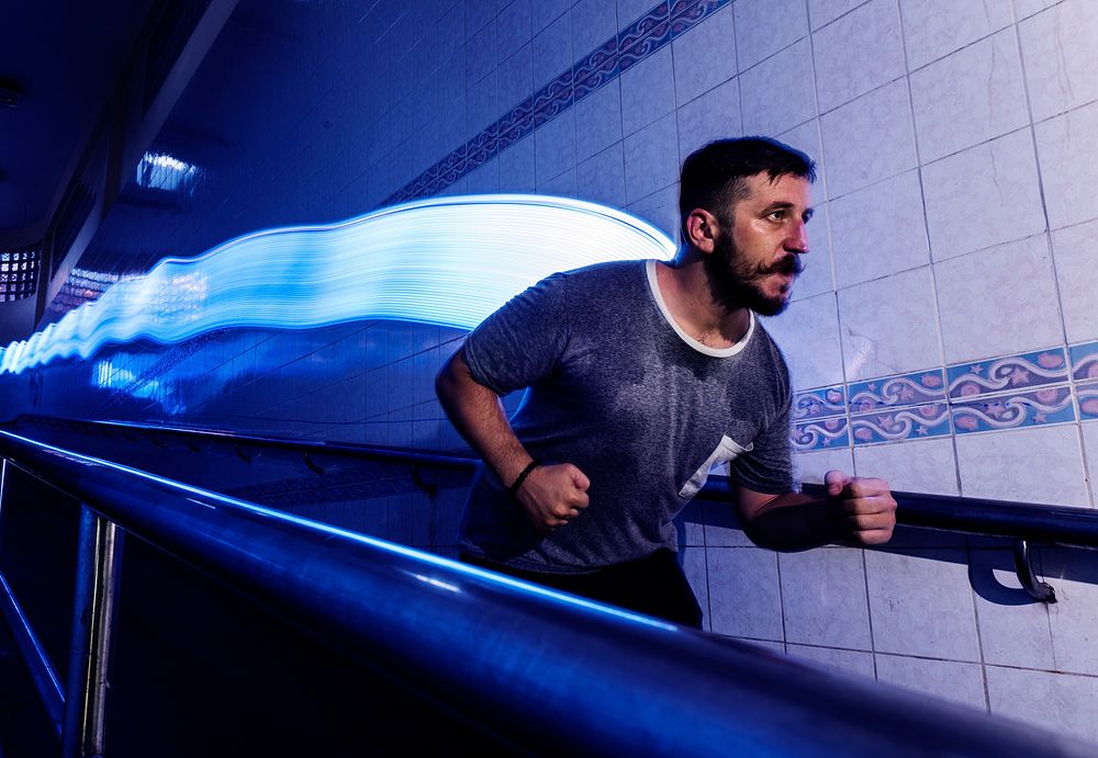 Man in a running movement with long exposure light at his back