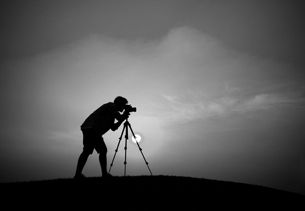 Silhouette of a guy taking a photo outdoors