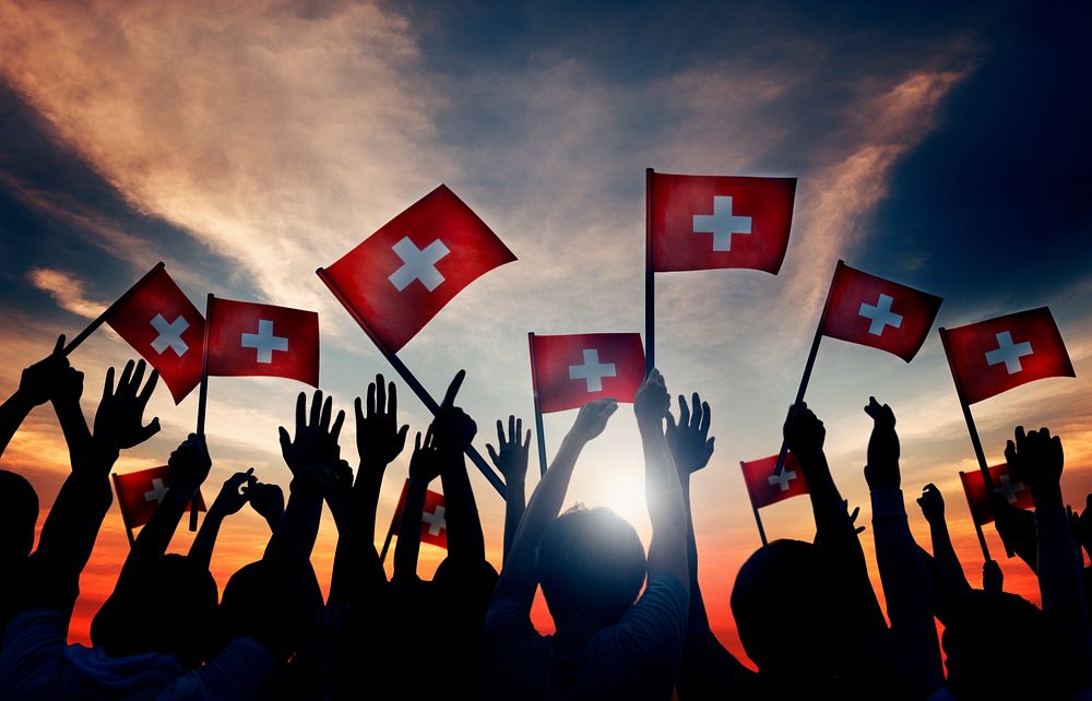 Group of People Waving Switzerland Flags in Back Lit