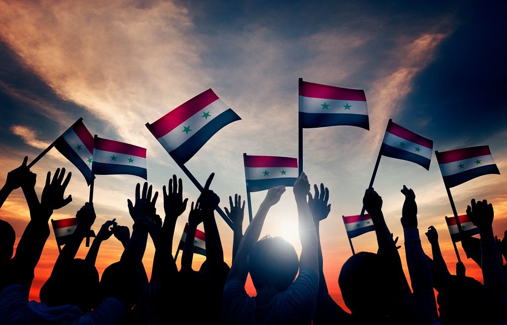 Group of People Waving Flag of Syria in Back Lit