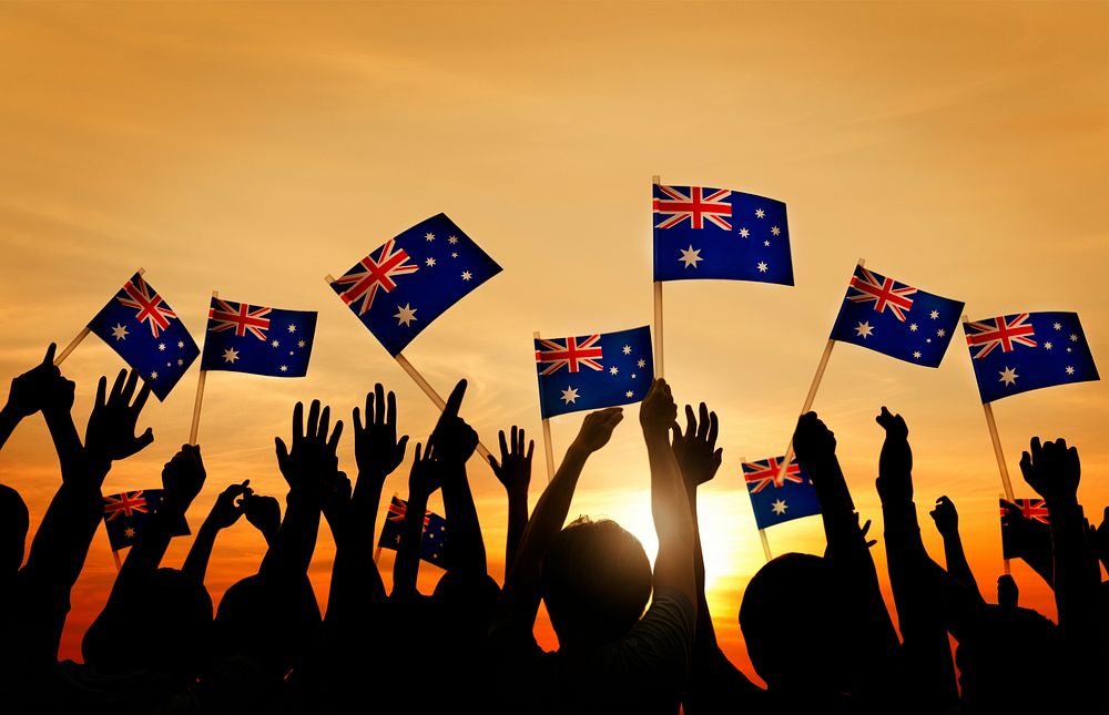 Group of People Waving Australian Flags in Back Lit