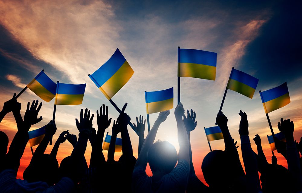 Group of People Waving Ukranian Flags in Back Lit