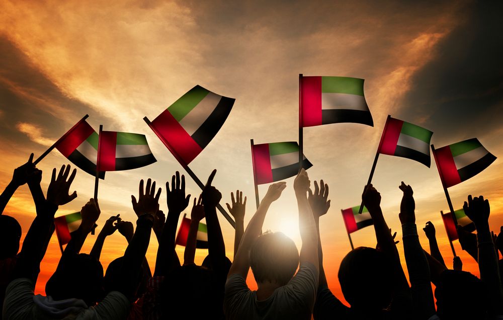 Group of People Waving Flag of UAE in Back Lit