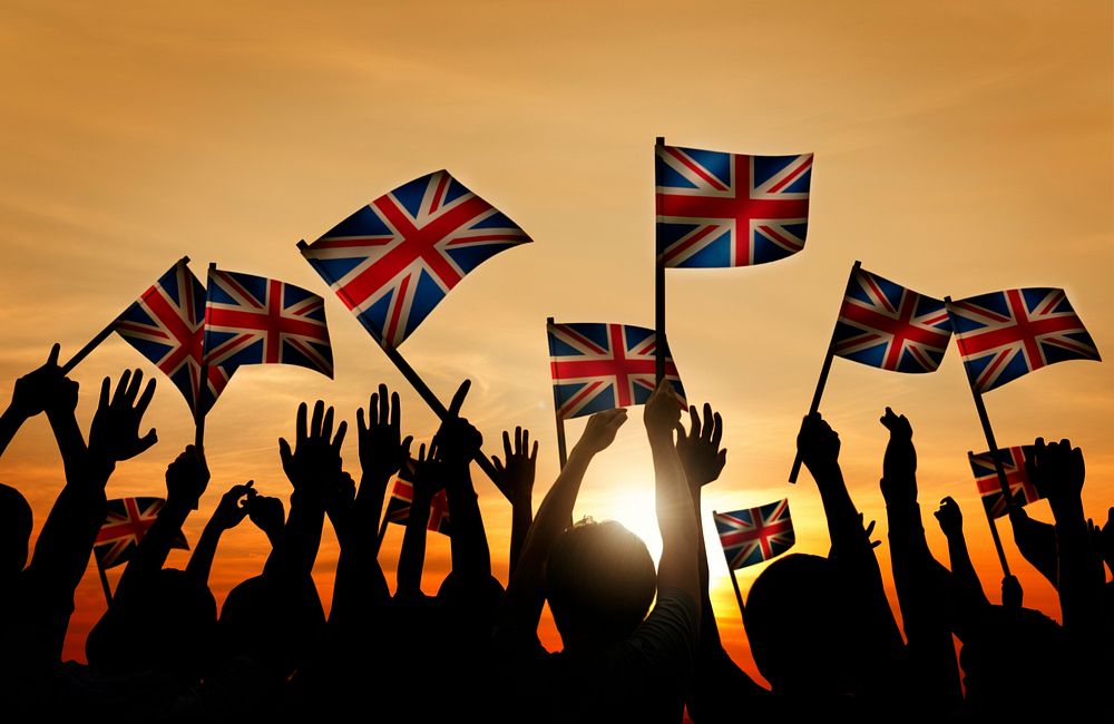 Group of People Waving UK Flags in Back Lit