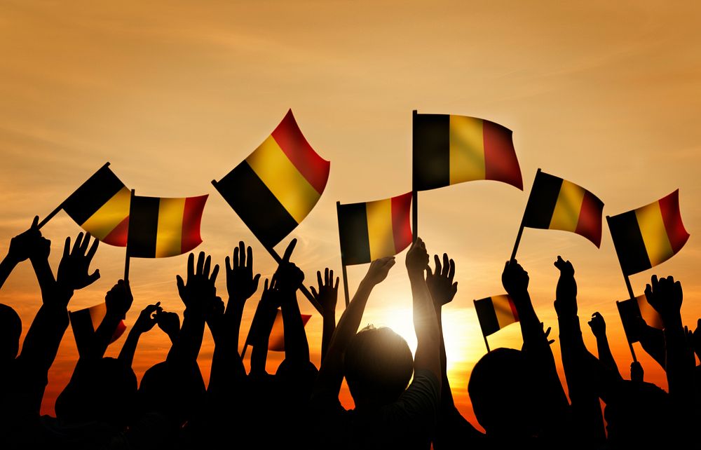 Group of People Waving Belgian Flags in Back Lit