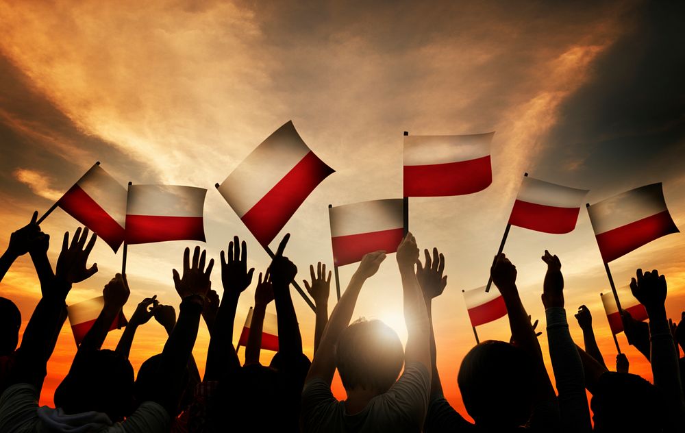 Group of People Waving Polish Flags in Back Lit