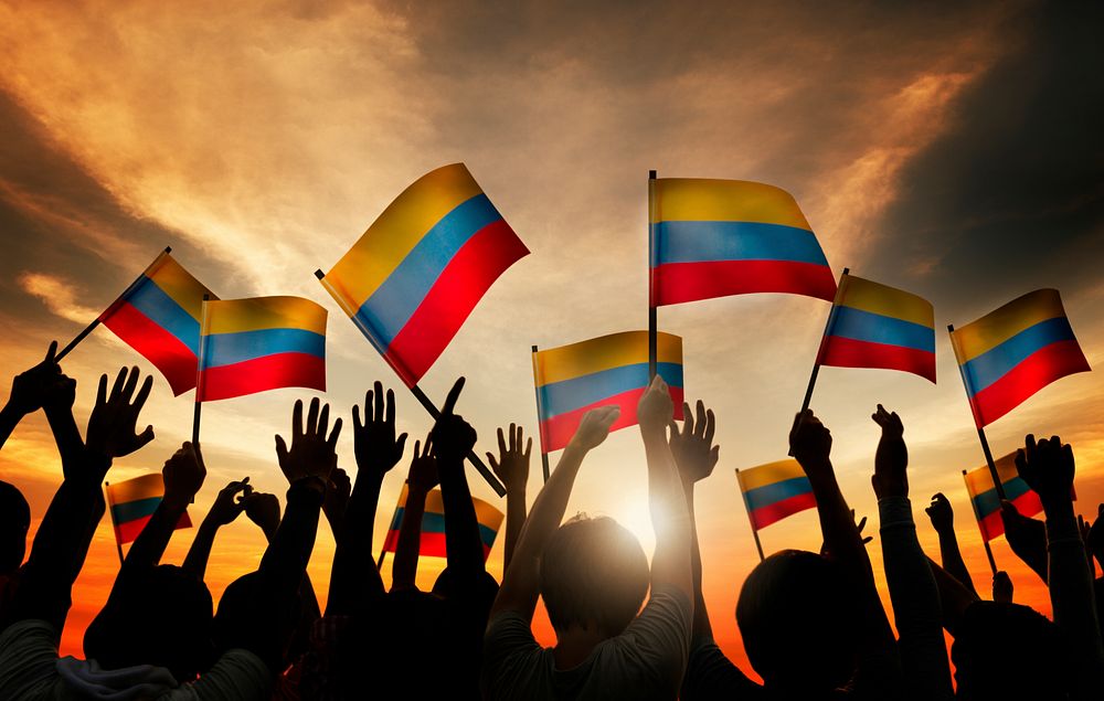 Group of People Waving Columbian Flags in Back Lit