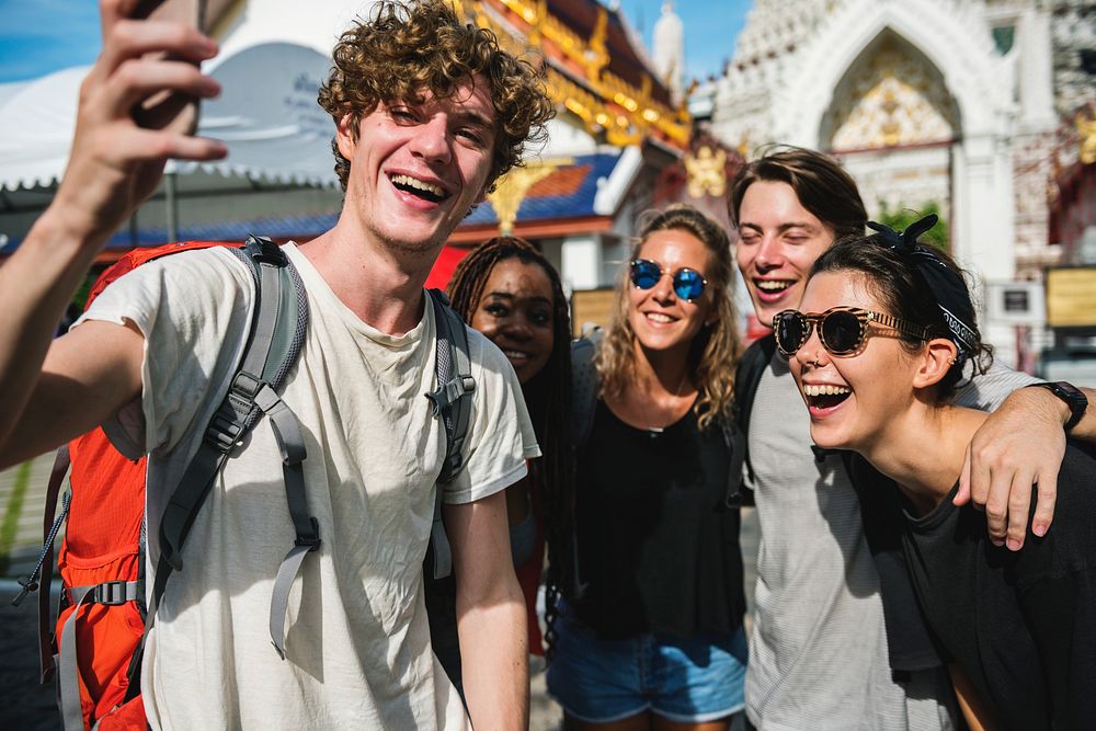 A group of diverse tourists taking selfie in front of a Thai temple, Thailand