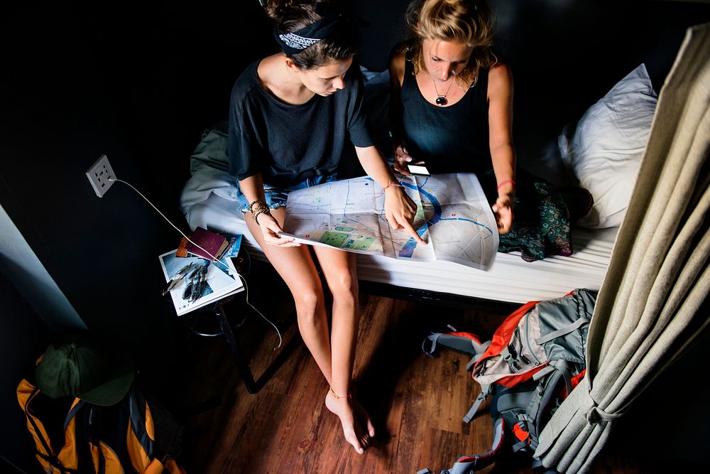 Two Caucasian tourists sitting on the bed looking at the map