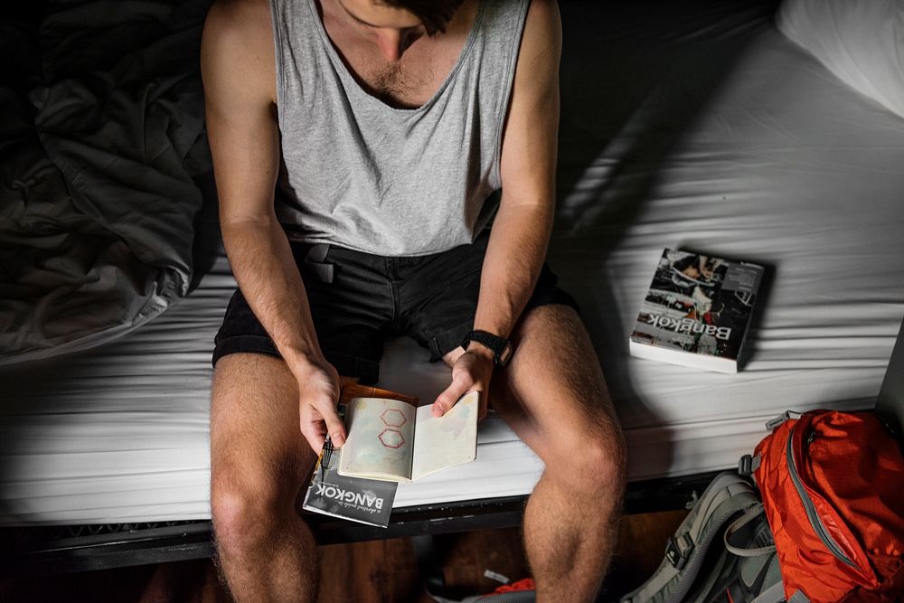 Backpacker sitting on the bed open his passport