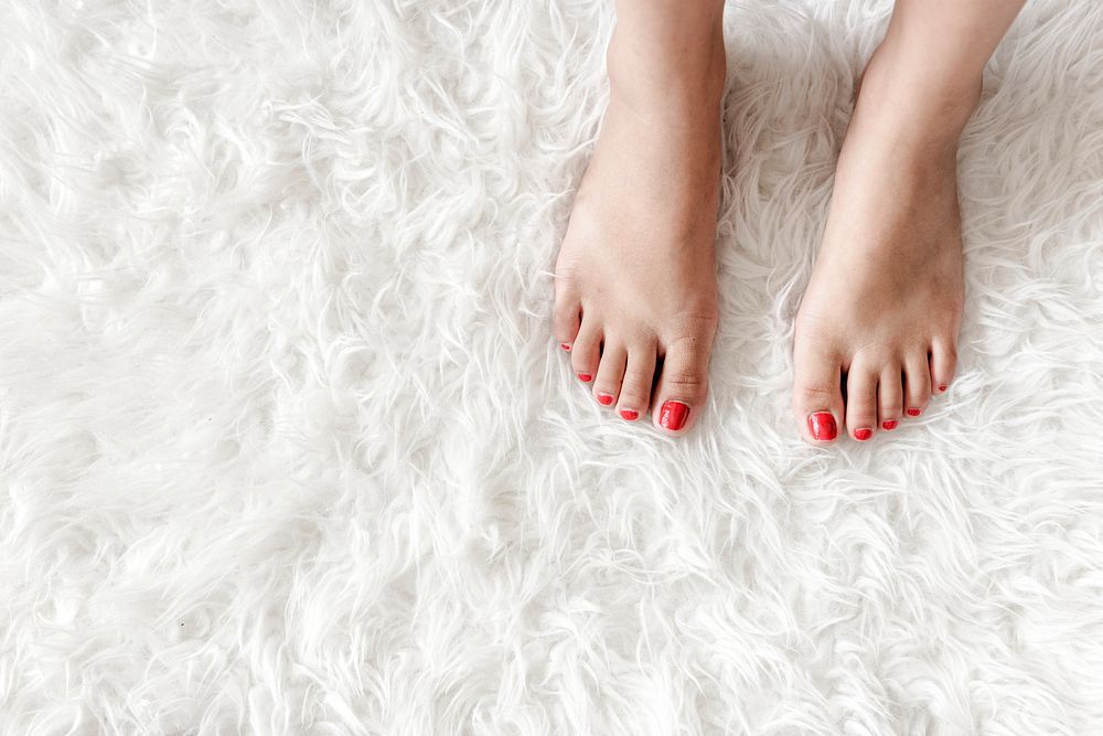 Closeup of woman legs on white fluffy carpet
