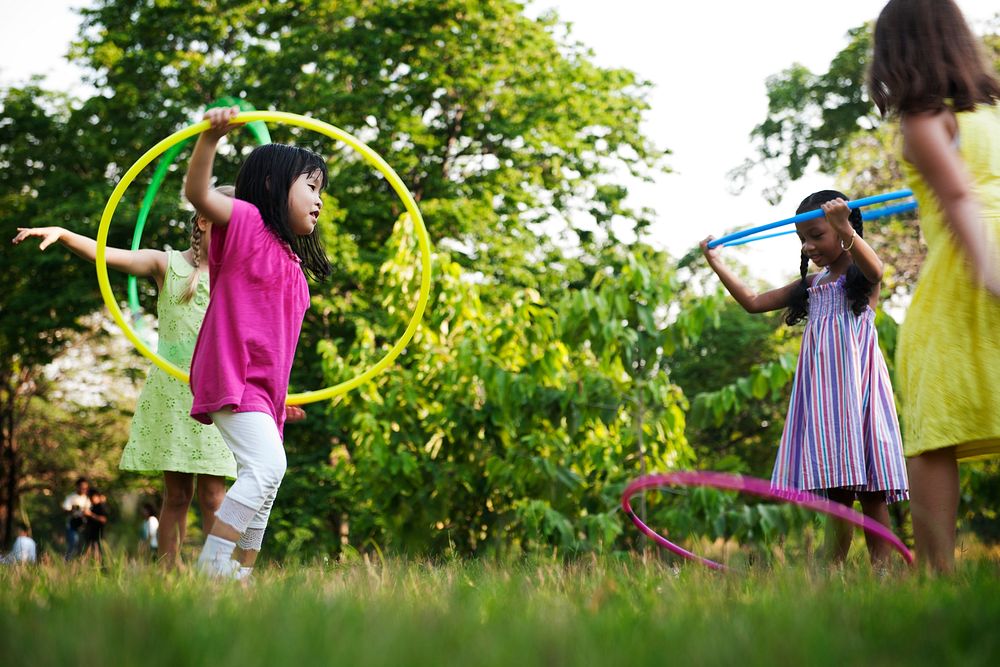 Group of diverse kids playing hula hoop in the park together
