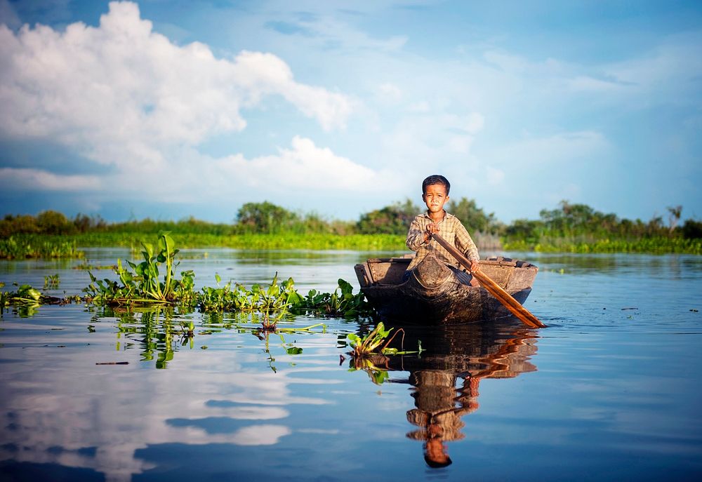 Cambodian boy traveling by boat in floating village