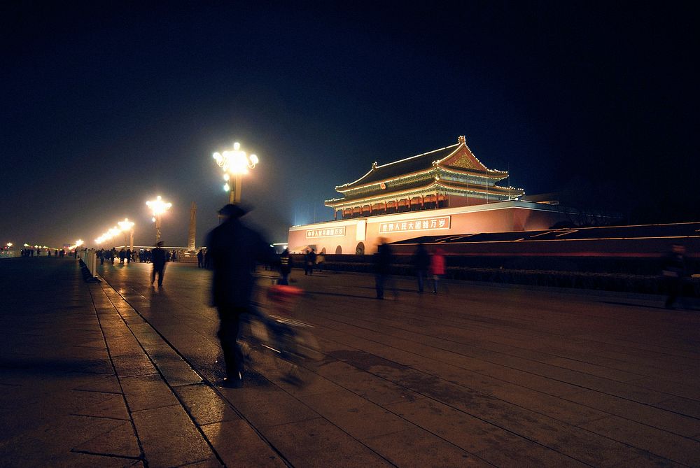 An elderly man walks past the gates to the Forbidden city.