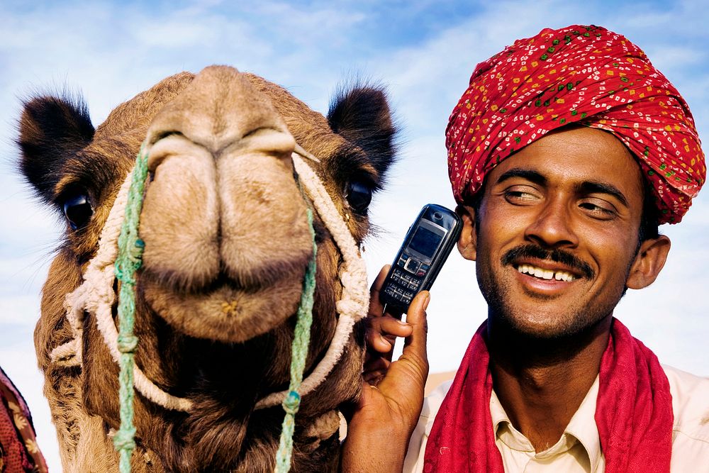 Indian man with camel talking on the phone