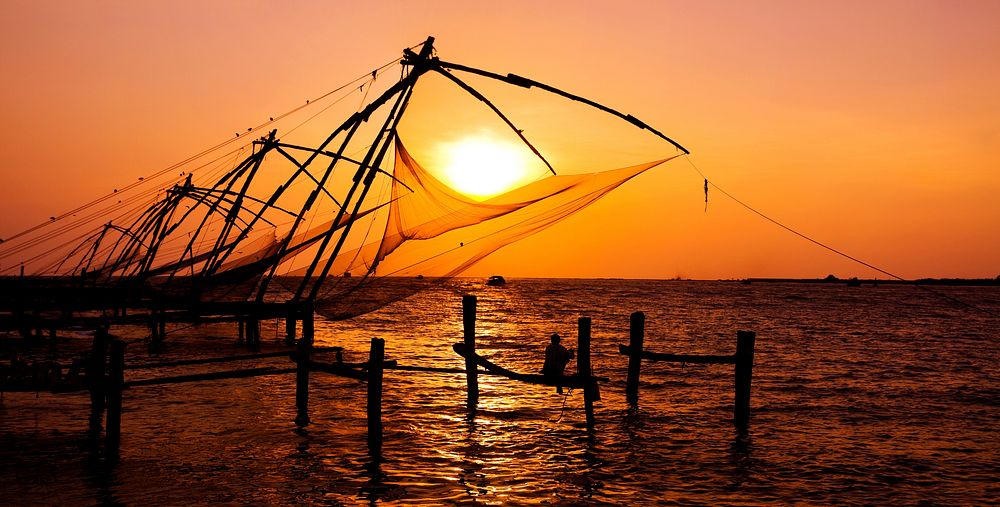Indian man fishing under the great Chinese nets at Cochin, Kerela, India