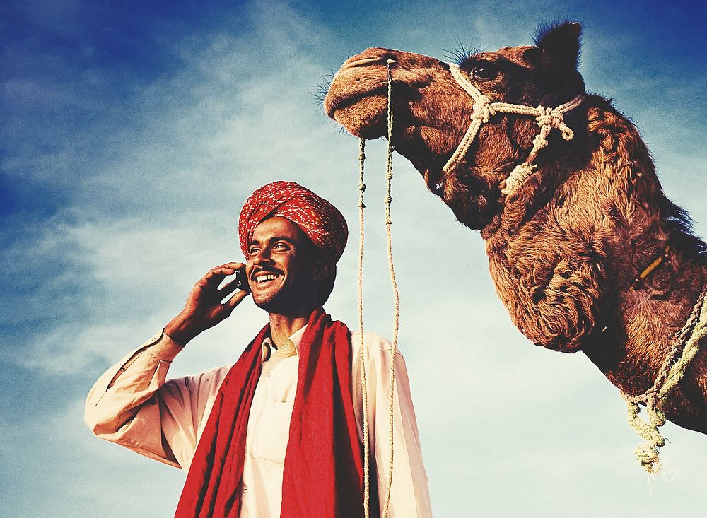 Indian man with a camel talking on the phone
