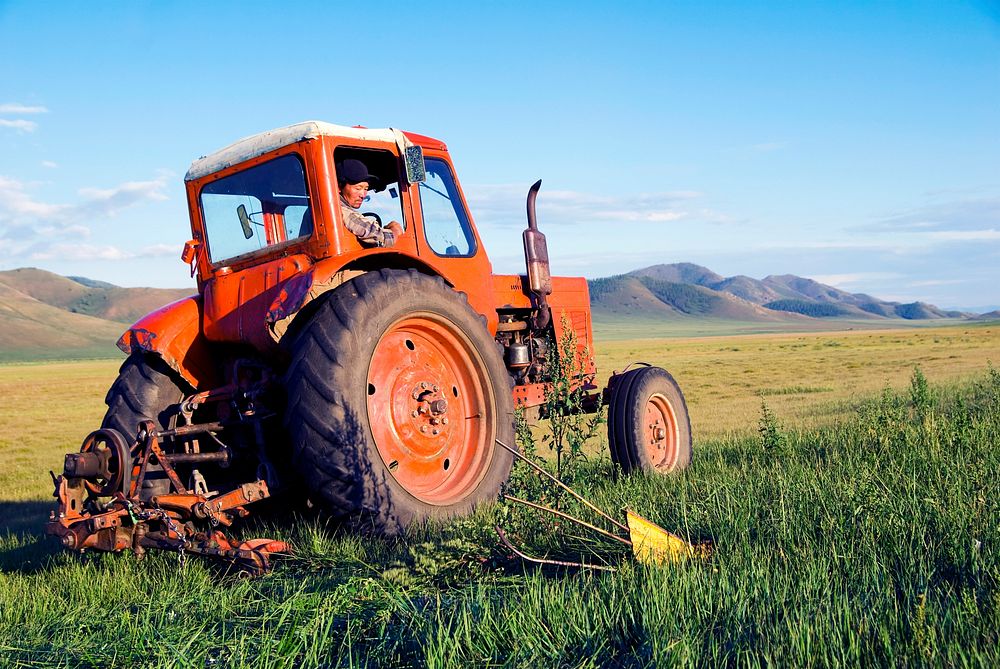 Mongolian farmer driving his tractor on the field.