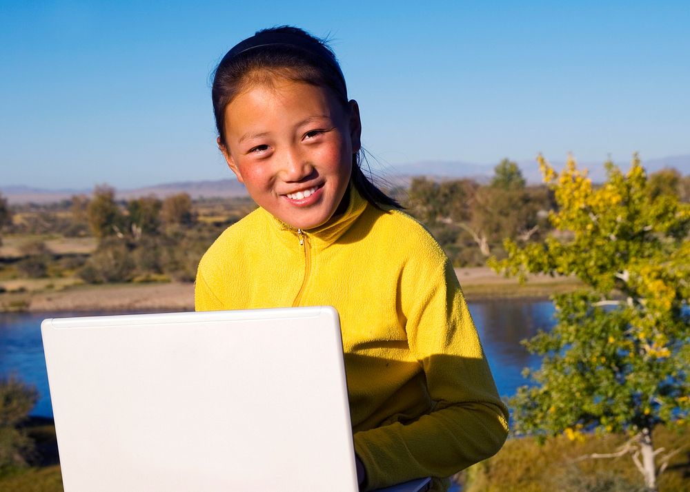 Mongolian girl with laptop by lake.
