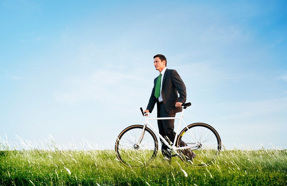Business man pushing a bike outdoors, green business and environmental concept