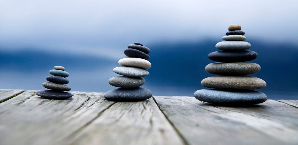Zen balancing pebbles next to a misty lake. 