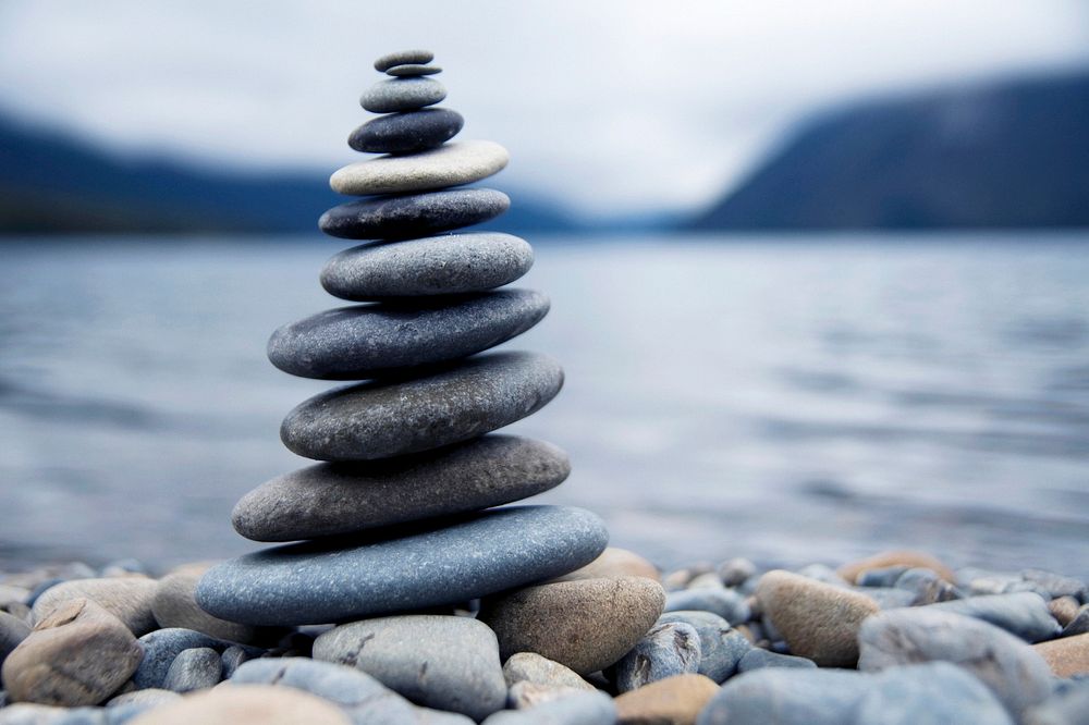 Zen balancing pebbles next to a misty lake.
