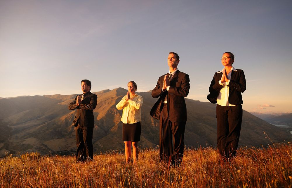 Business team meditating on Top of the mountains.