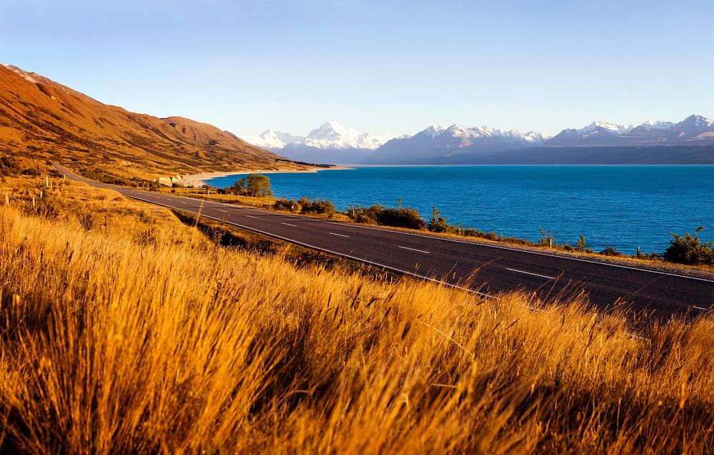Country road with amazing scenery of lake and a mountain range.